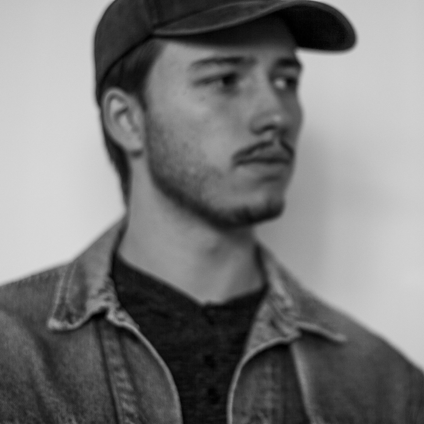 Black and white portrait of Campbell Shepard, Frederick, MD photographer, wearing a dark baseball cap and denim jacket
