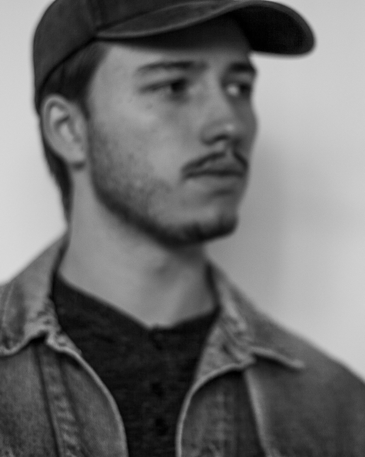 Black and white portrait of Campbell Shepard, Frederick, MD photographer, wearing a dark baseball cap and denim jacket