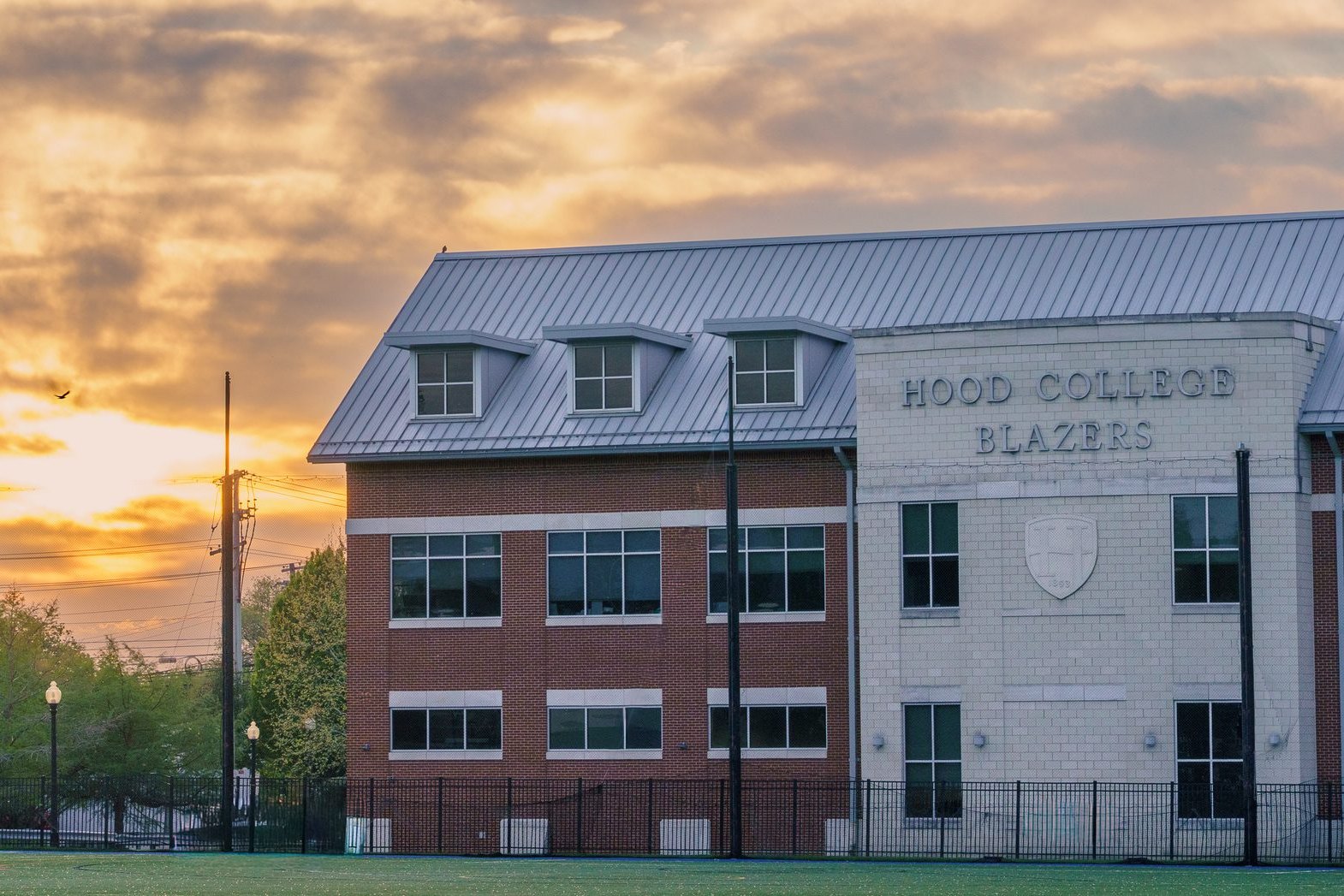 Hood College Blazers building at golden hour with a bird crossing the sunset, Frederick, MD, photograph by Campbell Shepard