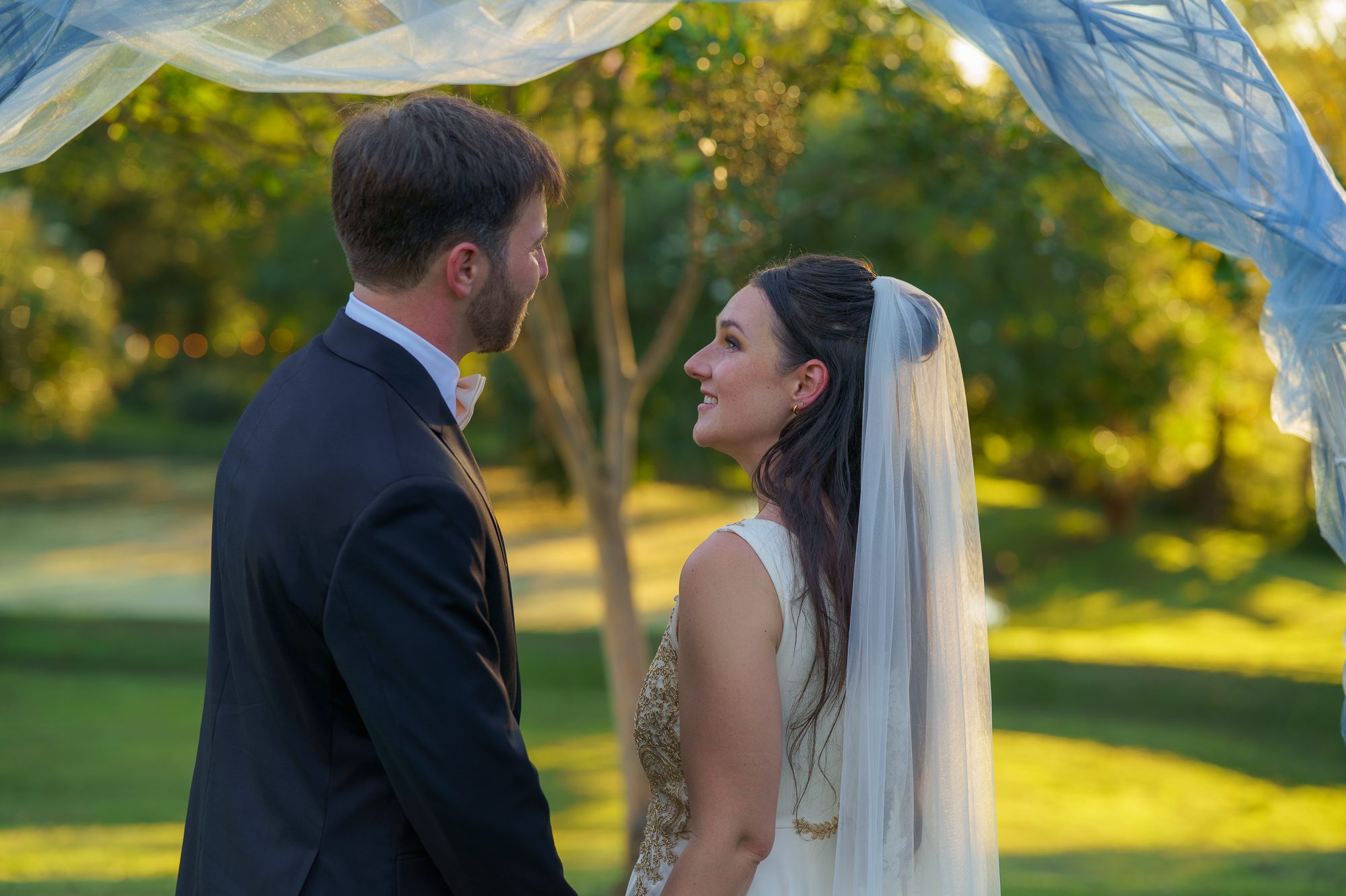 Two people in wedding attire outdoors among trees