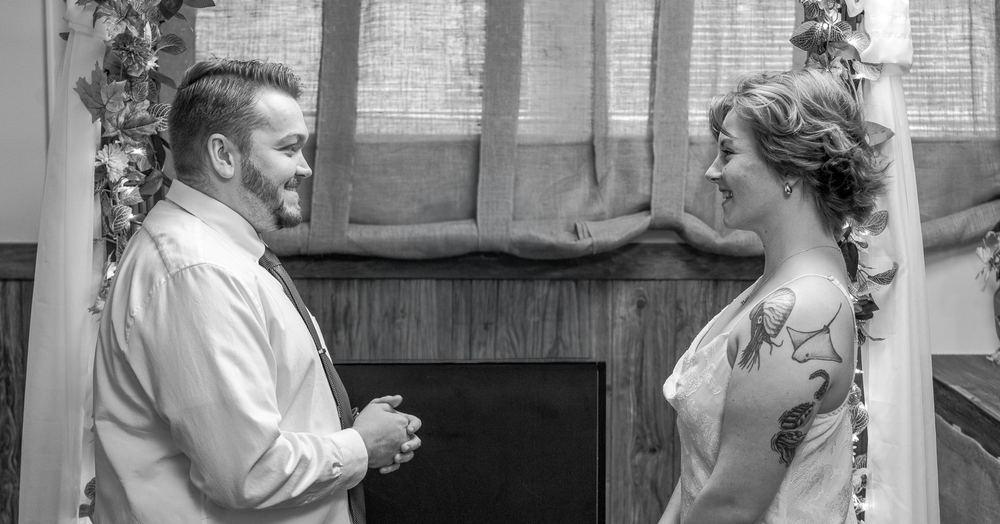 Black and white photograph of a bride and groom smiling at each other at the altar, wedding ceremony photography by Campbell Shepard, Frederick, MD