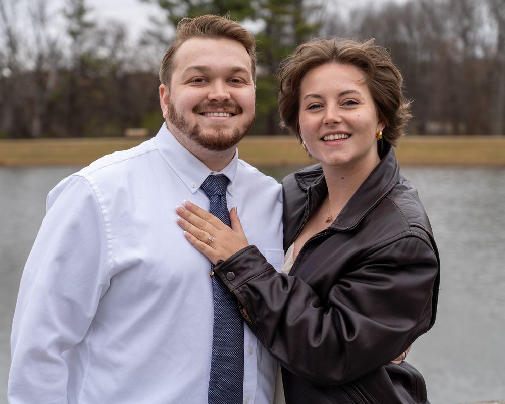 Newly engaged couple smiling at the camera beside a Frederick area lake, engagement photography by Campbell Shepard