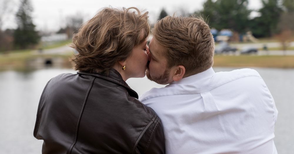Newly engaged couple kissing, viewed from behind, at a Frederick area park, engagement photography by Campbell Shepard