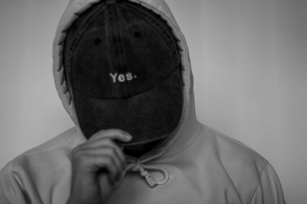 Moody studio portrait of a man in a hoodie and cap reading Yes, portrait photography by Campbell Shepard, Frederick, MD